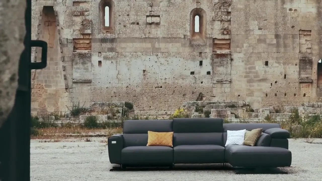 Il divano Dogma Emerald Edition in pelle scura tra le mura in pietra di un castello