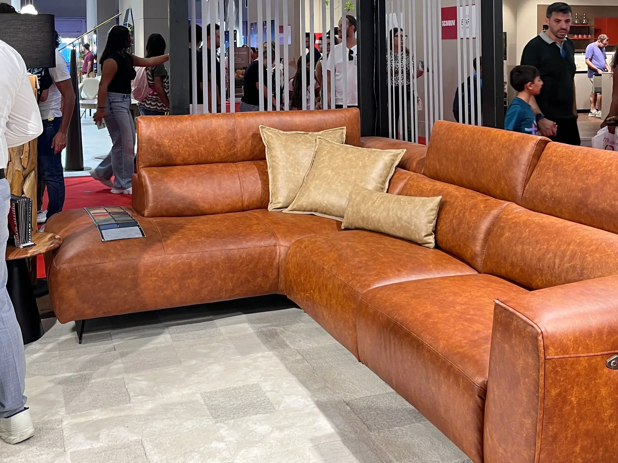Divano angolare color cuoio con cuscini dorati, esposto allo stand Merolla