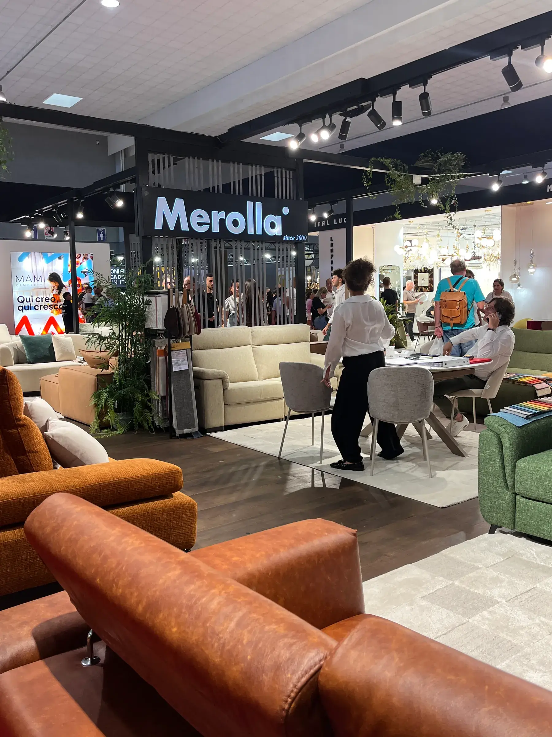 Lo stand Merolla alla Fiera del Levante 2026: l’insegna luminosa, i divani esposti e il tavolo dove si scelgono i tessuti