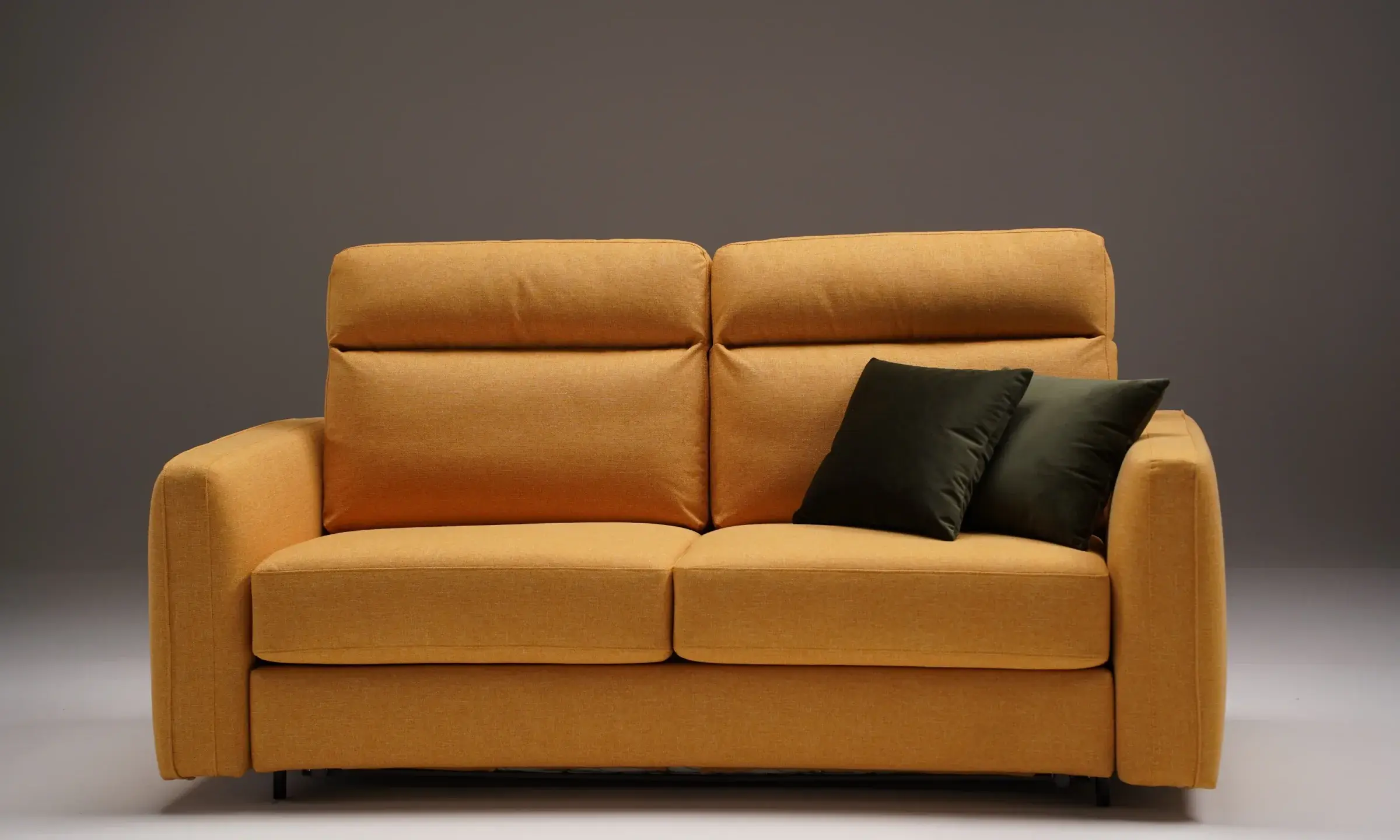 Divano letto Pegasus giallo senape con poggiatesta regolabili, vista frontale in studio