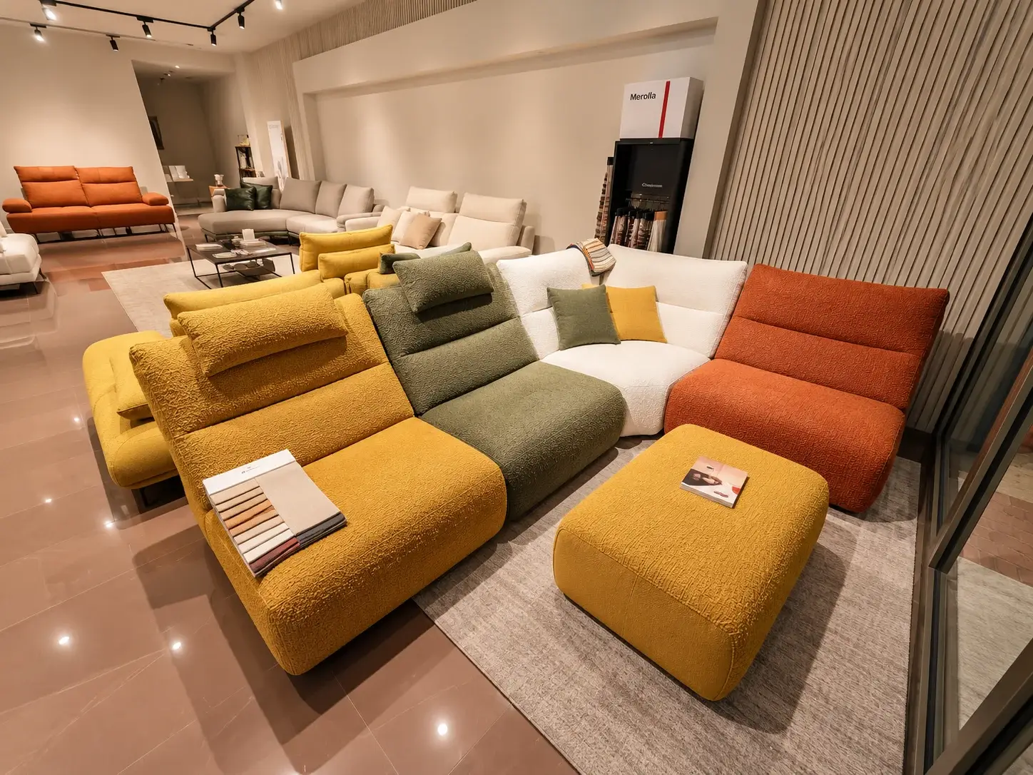 Divano modulare con moduli giallo senape, verde salvia, bianco e arancio, con pouf, nello showroom Merolla