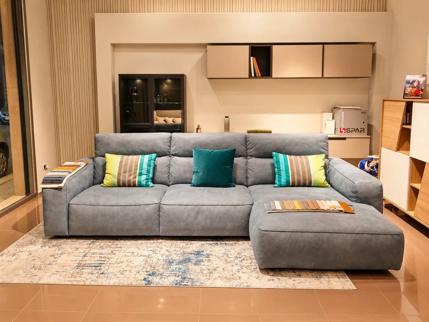 Divano blu-grigio con penisola e cuscini colorati in un angolo living dello showroom
