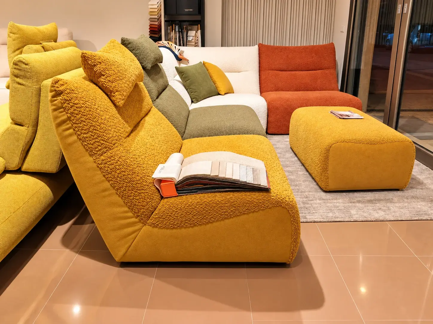 Composizione modulare colorata con chaise longue gialla e pouf nello showroom