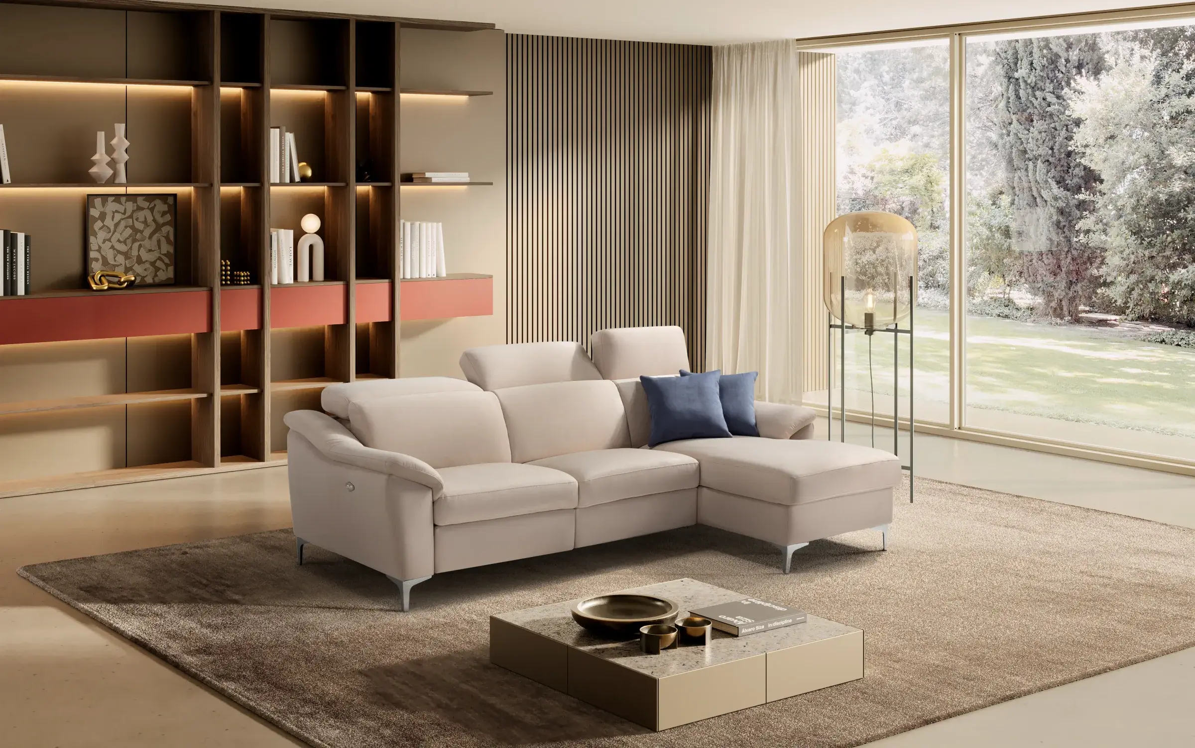 Divano Urano beige con penisola in un living con libreria illuminata